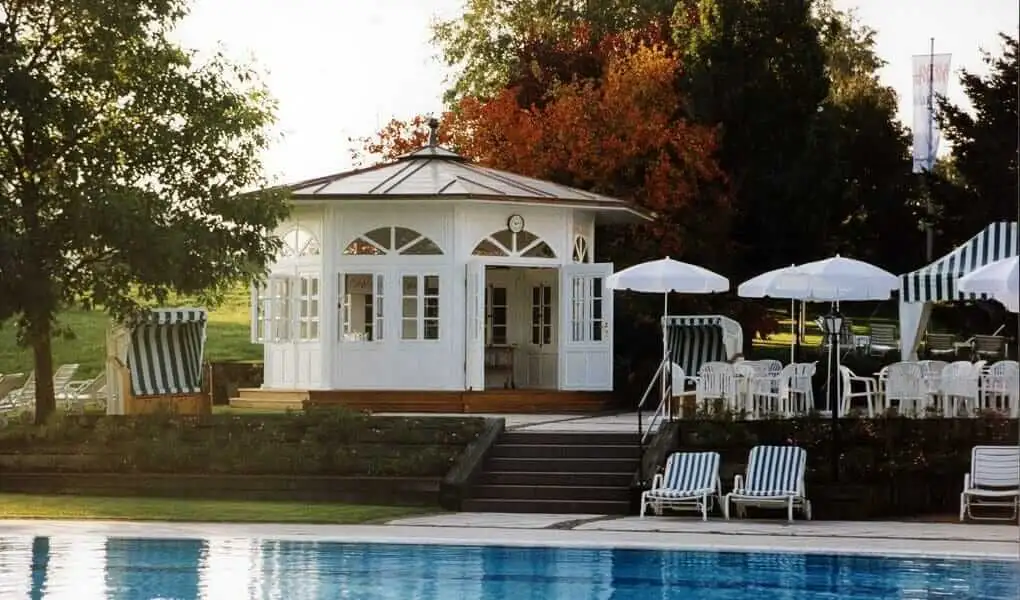 Weißer achteckiger Pavillon mit Rundbogenfenstern an einem Hotelpool
